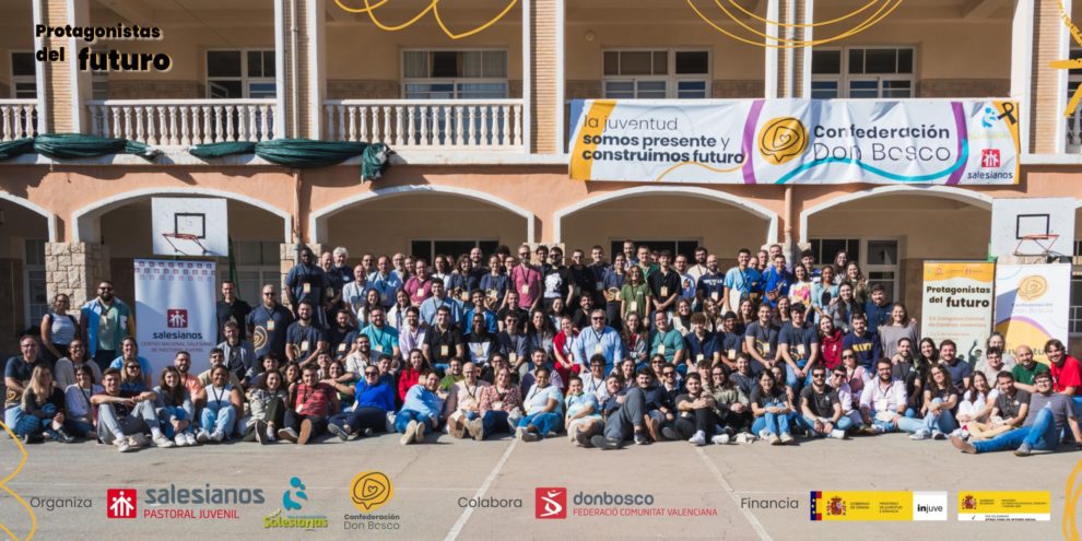Foto grupal de participantes en un evento juvenil de Salesianos y Confederación Don Bosco, con banners que destacan colaboración y patrocinios
